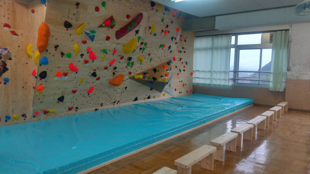 小学校のボルダリング壁下に設置した大型安全マットを斜めから撮影した写真